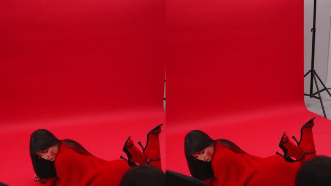 一名女摄影师拍摄了一名亚洲模特，她身穿红色毛衣和连裤袜，趴在红色背景的地板上。艺妓穿着红色的衣服。垂