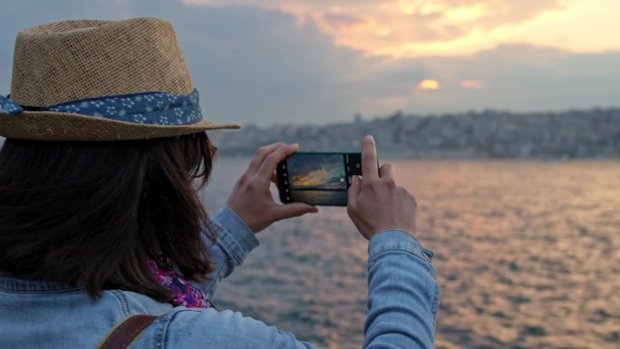 日落时分，年轻女子在伊斯坦布尔的桥上拍照
