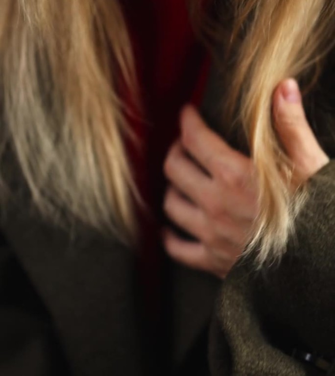 女孩的手修补外套的特写。垂直视频。红毛衣