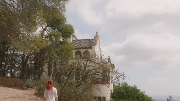 一名女子正走向安东尼·高迪设计的巴塞罗那Guell公园的Casa Trias