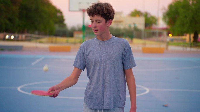 少年拿着乒乓球拍，弹着乒乓球。慢动作电影剪辑与运动器材