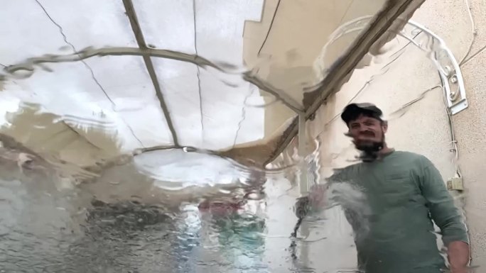 男子用加压射流清洗汽车挡风玻璃。在人工洗车服务中，流动的水模糊了玻璃。从内部近距离观察。高质量的全高