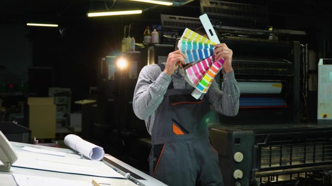 在印刷工厂，滑稽的设计师手拿色板跳舞