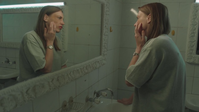 脸上有淤青和抓痕的女人看着镜子里的自己
