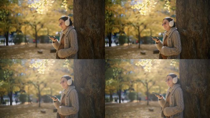 秋天，孕妇倚在树上，一边用智能手机一边听播客