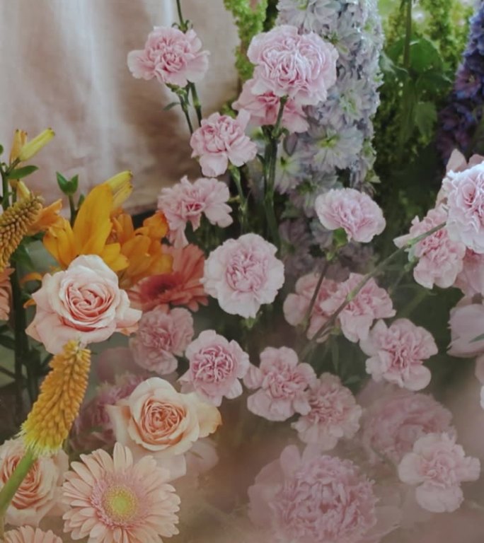 垂直视频特写婚礼花艺装饰与新鲜的彩色鲜花靠近新娘和新郎的桌子，美丽的鲜花安排婚礼，慢动作。