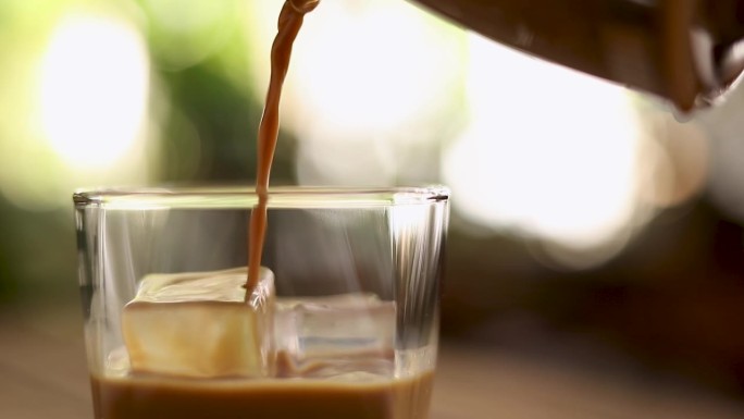 将浓缩咖啡倒入加冰的玻璃杯中。在玻璃杯中加入冰块的现煮咖啡。