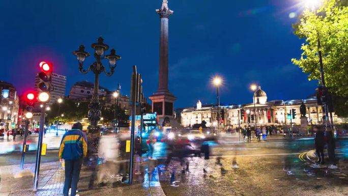 人群交通和通勤游客在特拉法加广场步行和过马路的时间流逝，这是英国伦敦市中心威斯敏斯特市夜间的公共广场