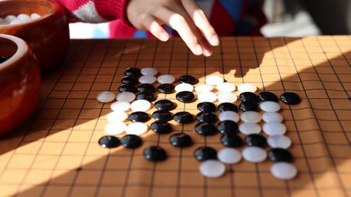 中国小孩在窗边下棋围棋手部特写