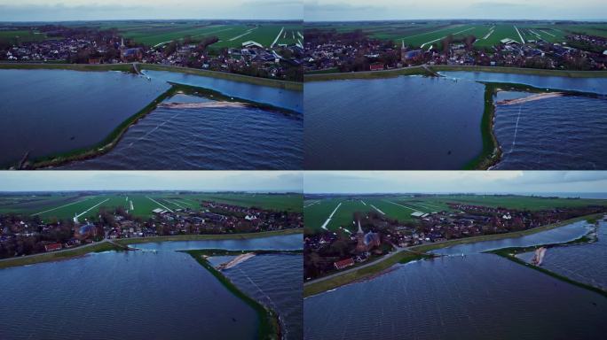 在蓝色的马克米尔湖的大堤后面，荷兰一个村庄被洪水淹没的海滩的空中轨道拍摄