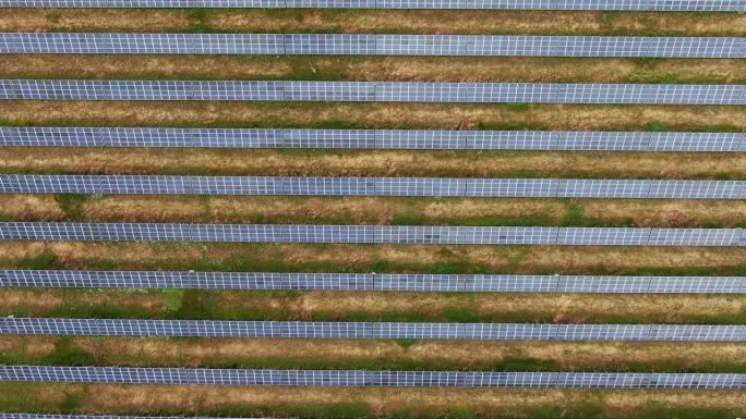太阳能电池板向前移动的鸟瞰图。缓慢的运动。运动方向垂直于面板的排列。可再生能源。绿色能源。世界环境规