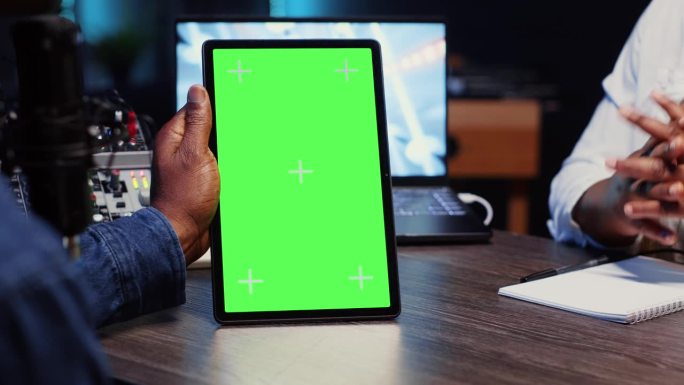 视频博主手持绿屏平板，在霓虹灯华丽的工作室里与嘉宾聊天