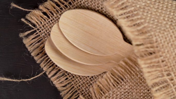 木制勺子由竹制环保材料和质朴的麻袋布在棕色的桌子上
