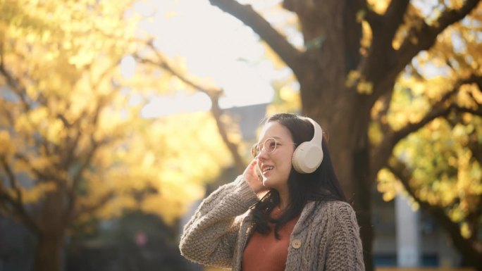 秋天，一位年轻女子在公园里听音乐