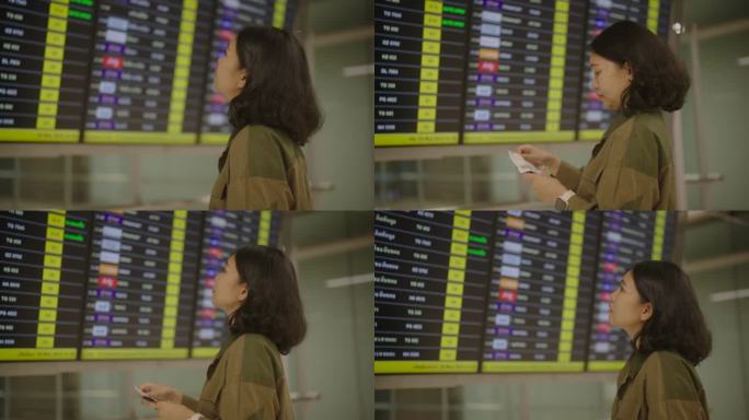 一名亚洲妇女在机场候机楼查看航班时刻表。