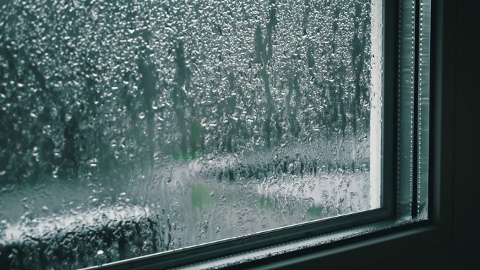 阴天里雨滴顺着窗玻璃流下来