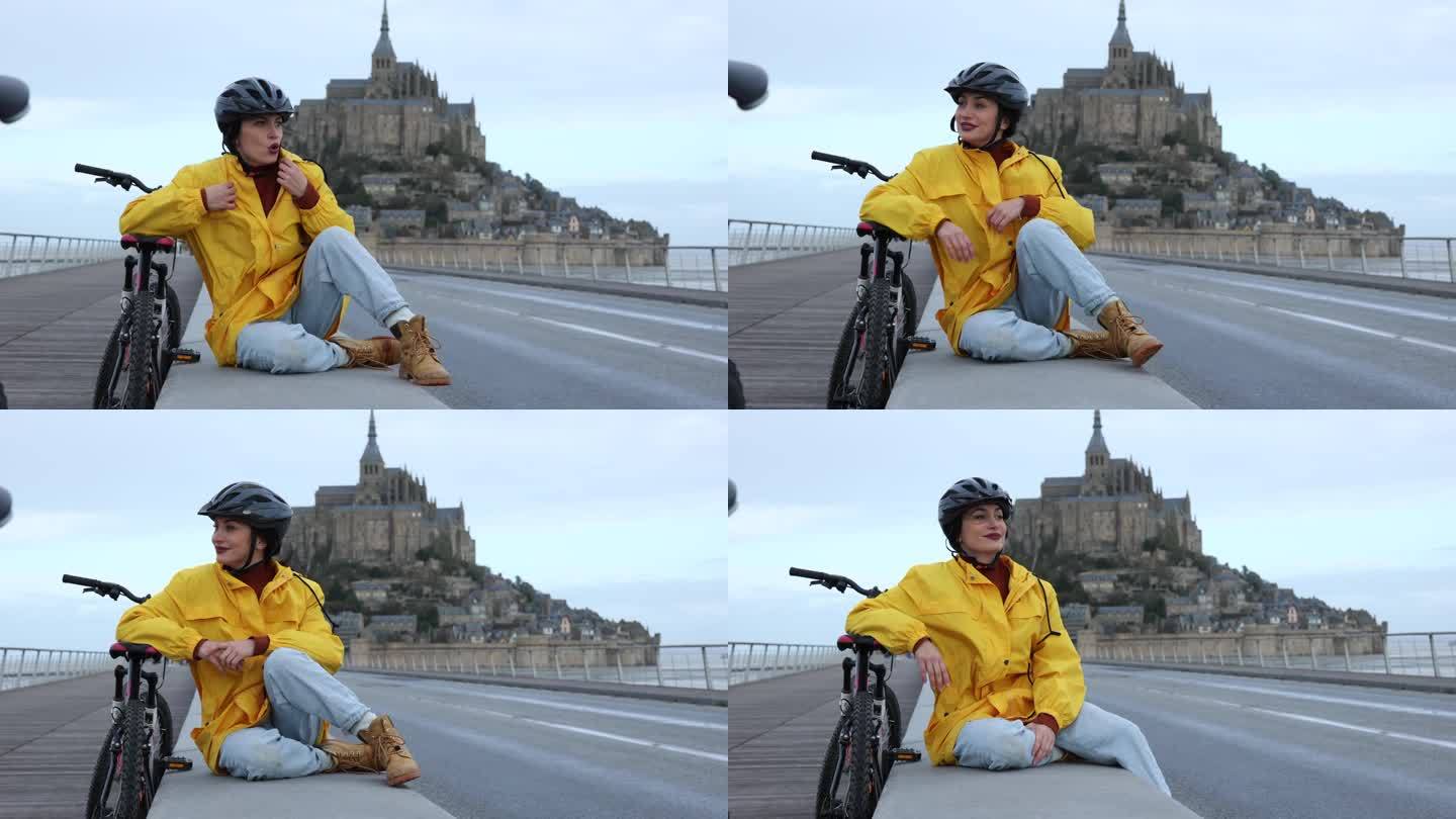 一个穿着彩色雨衣的女人靠在自行车上，因为天冷