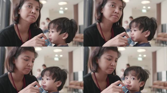 亚洲母亲给男婴喂一盒牛奶。