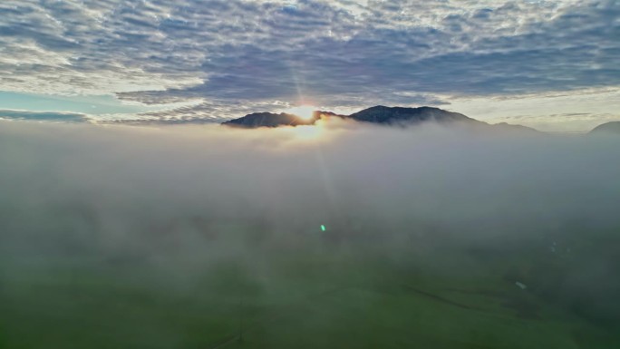 日出在山峰之上，同时在云层之上飞行，但在大气层的卷积云层之下