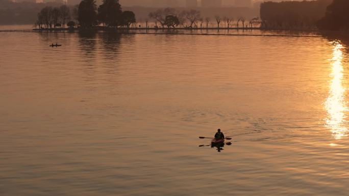 在东湖的夕阳下划船的游客