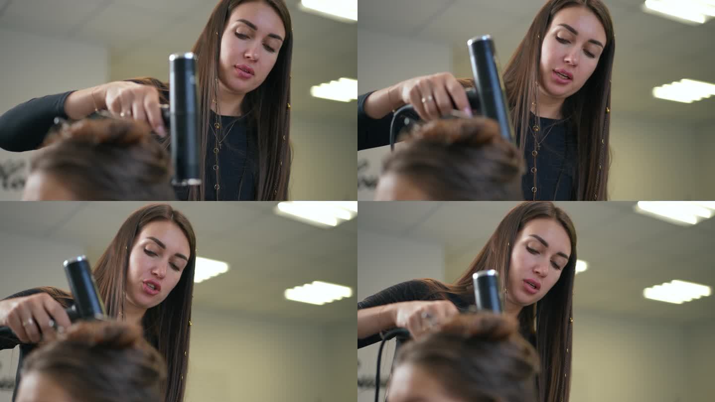 一位女性毛发学家正在吹干一位女性顾客的湿头发，并向她解释正确的做法。