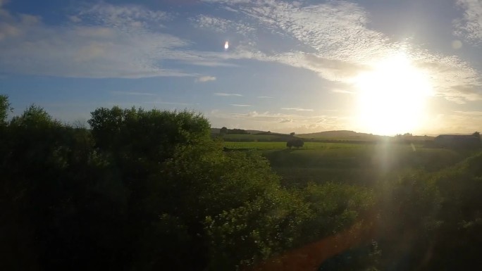 金色的晨光透过火车窗户照进绿色的苏格兰乡村