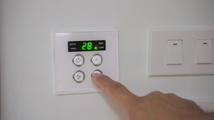 酒店房间空调控制面板。一个人的特写手将空调温度调到25摄氏度。