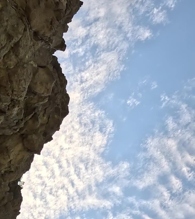 延时夏日天空。卷云漂浮在海上的晴空中，从洞穴中观看，前景是岩石。抽象的空中自然夏日天空。天气和气候变