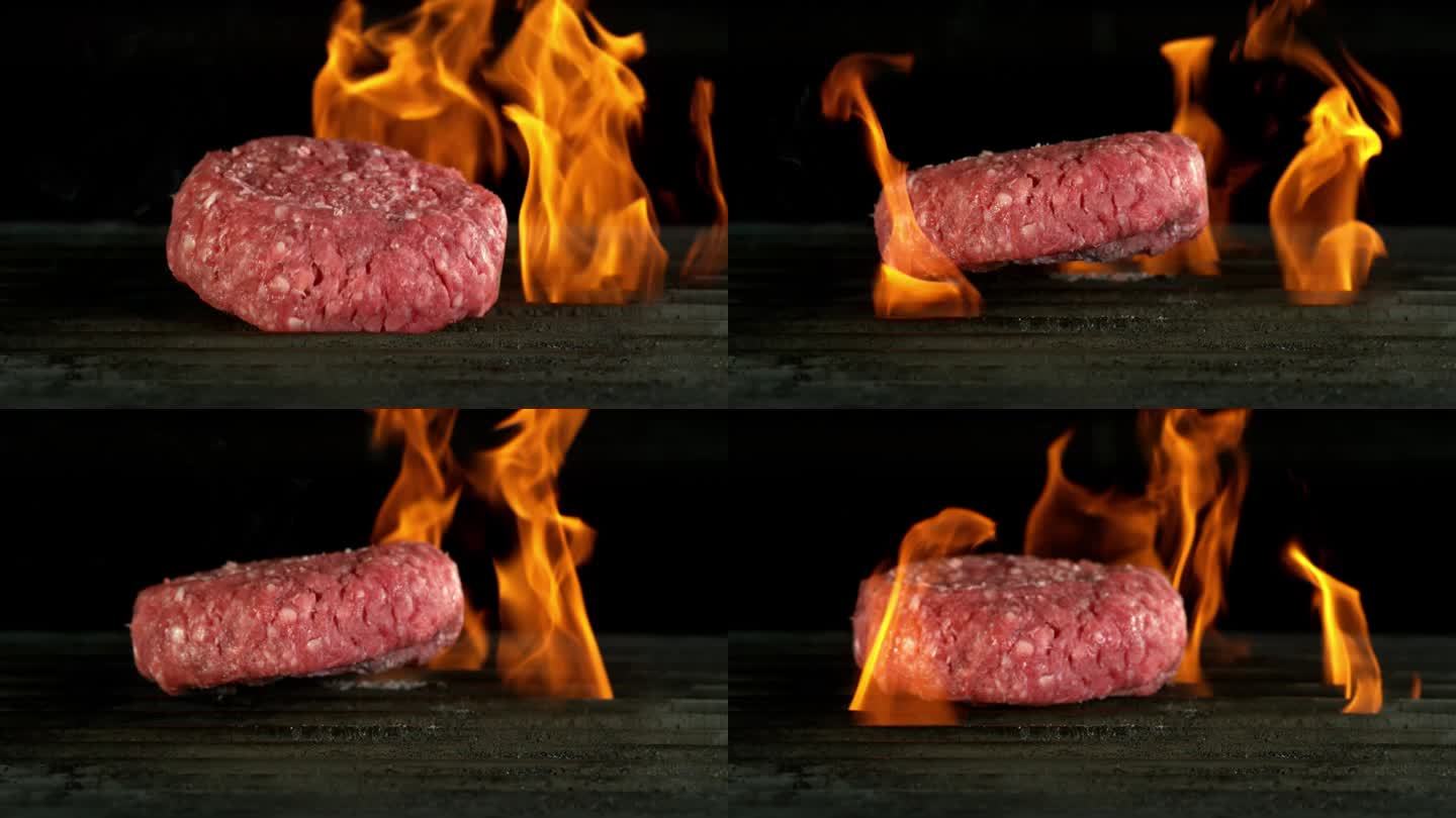 超级慢动作的牛肉碎餐在火上烧烤，黑色背景。