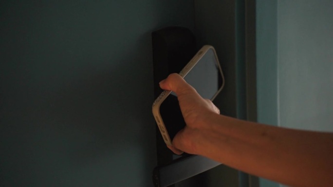 一个女人用智能手机触摸打开酒店房门的特写镜头。