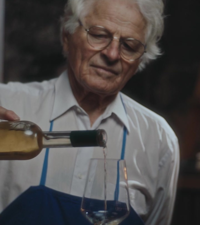 SLO MO年份提升:一位年长的侍酒师将白葡萄酒倒入玻璃杯中，酒厂，葡萄酒，葡萄酒商。斯洛文尼亚普雷