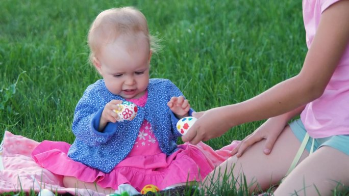 女孩带着小妹妹在草地上敲鸡蛋