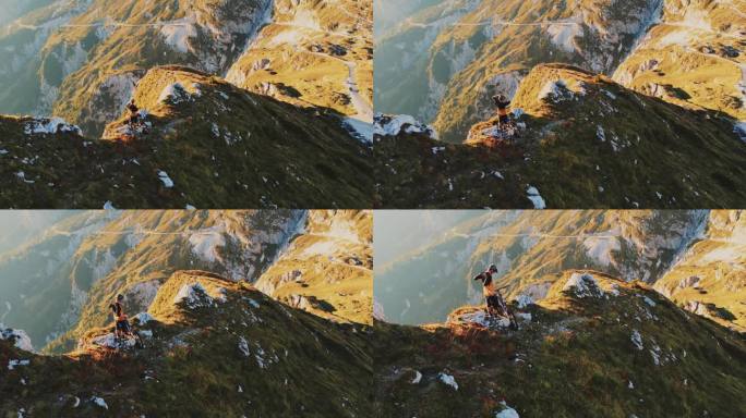 在阳光明媚的日子里，骑自行车的人站在巨大的悬崖边，高角度无人机拍摄