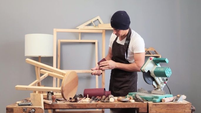 木材工业技能。掌握木材的艺术。工匠系着围裙，戴着帽子，用砂纸打磨木制品，将复杂的木制品图案赋予生命