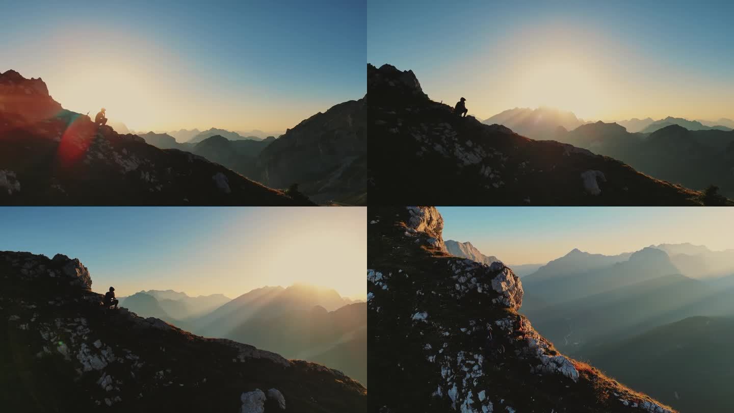 在阳光明媚的日子里，山地自行车手坐在巨大的悬崖边，用智能手机拍摄的无人机