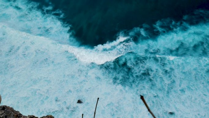 蓝绿色的海洋海水白色的波浪溅深蓝色的大海。鸟瞰怪物波浪飞溅在岩石上。热带海滩在夏季海边户外。大洋岛风