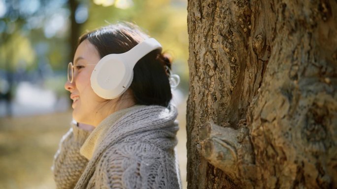 一个年轻女子在公园里听音乐的特写镜头