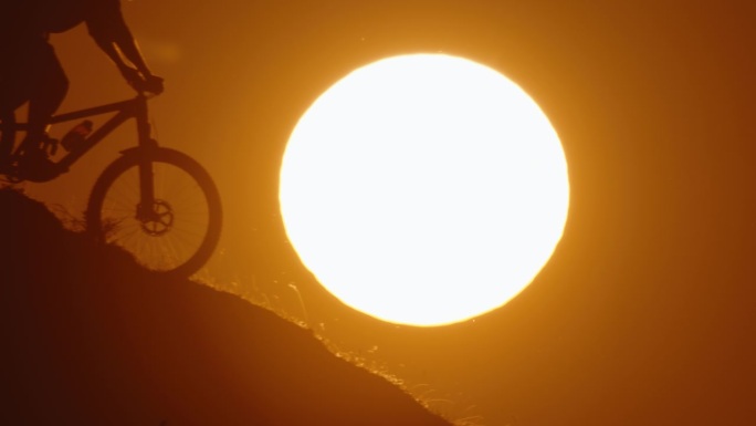SLO MO剪影山地自行车自行车下坡对雄伟的太阳在晴朗的天空在日落