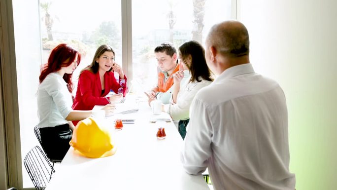 一群建筑师和工程师围着一张桌子讨论建筑计划。