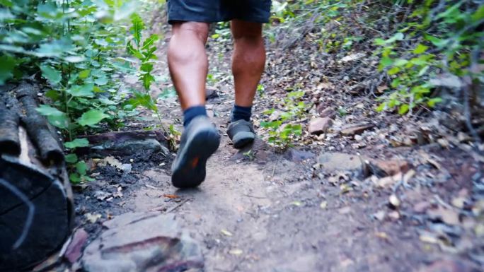 人们在大自然中远足、散步、穿鞋，度假放松身心，健康环保。徒步旅行，健身和健康与人的腿走在森林小径冒险