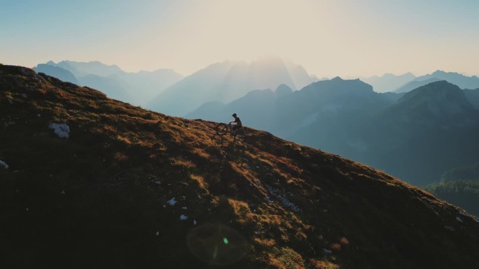 在晴朗的蓝天下，坚定的男性骑自行车者在大山上移动的无人机镜头