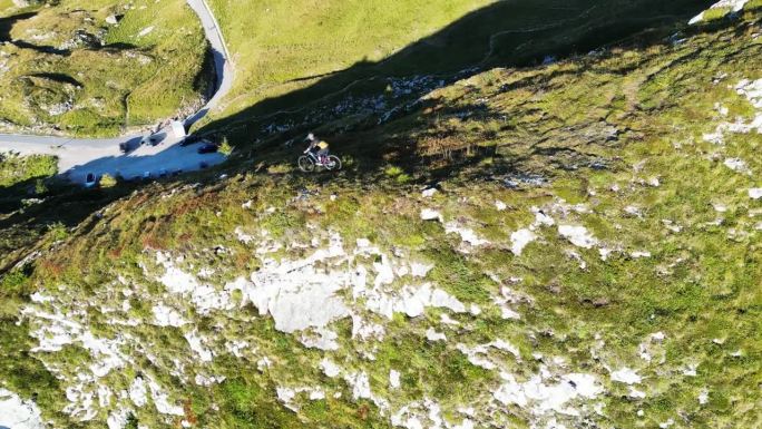 空中无人机拍摄的决心骑自行车在大岩石悬崖在晴朗的日子对晴朗的蓝天