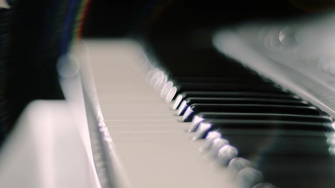 在背光下闪闪发光的合成器键盘(钢琴)上弹奏的女性双手