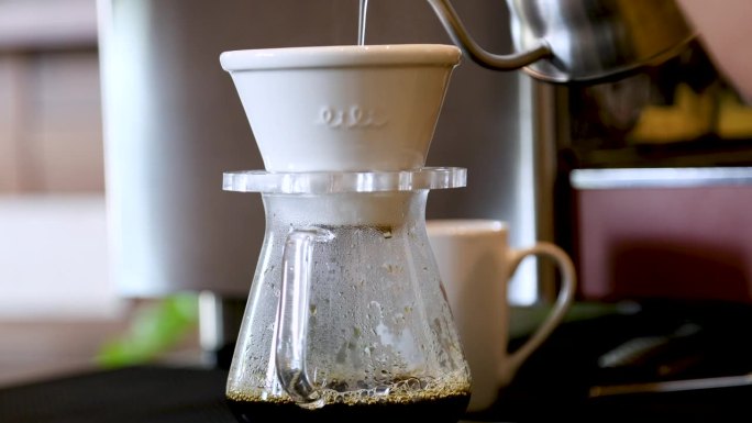4k，咖啡点滴设备中压力豆粉的热咖啡水滴特写，上菜前手工将咖啡滴入玻璃杯的过程，咖啡点滴爱好者的生活