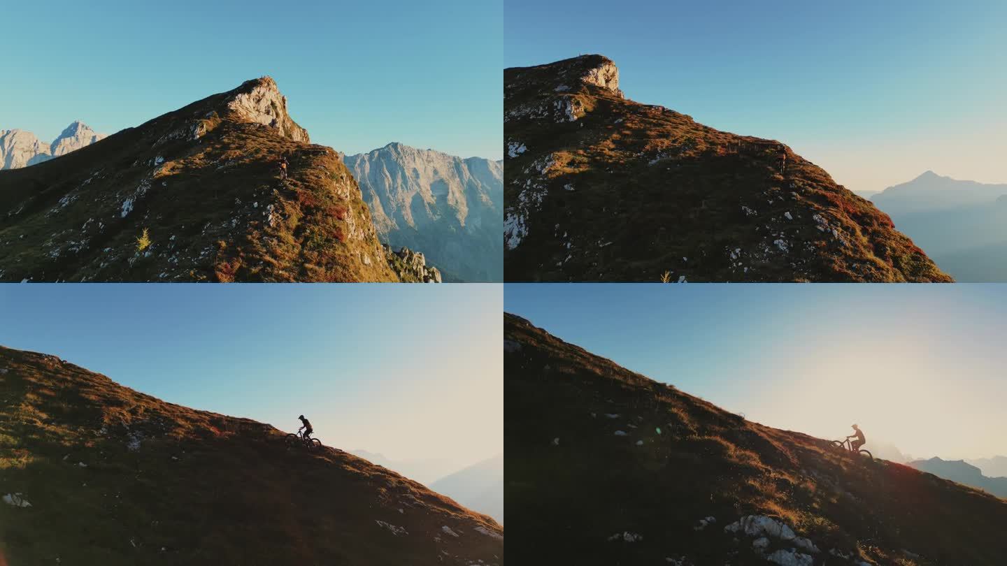 在阳光明媚的日子里，山地自行车手在巨大的岩石悬崖上骑自行车的无人机镜头