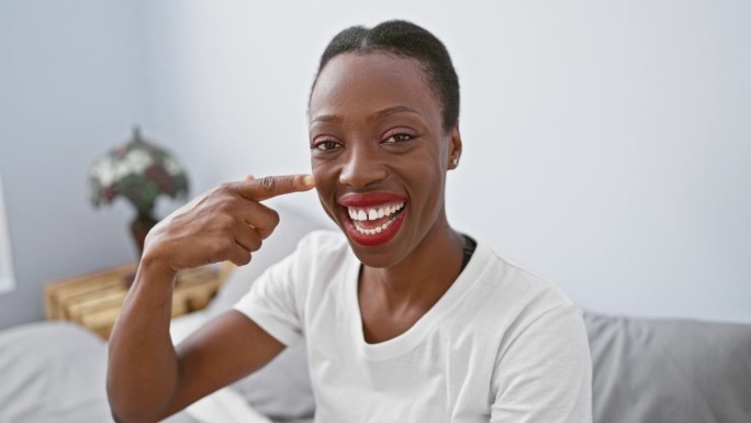 一个非洲裔美国女人躺在床上，微笑着用手指着脸和鼻子，散发着美丽的光芒