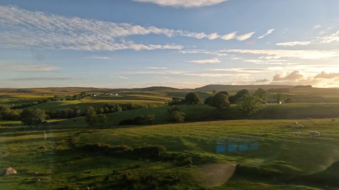在金色的夕阳下，乘坐风景优美的火车穿过苏格兰乡村连绵起伏的山丘