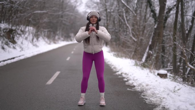 冬季，女运动员站在大自然的道路上做热身运动