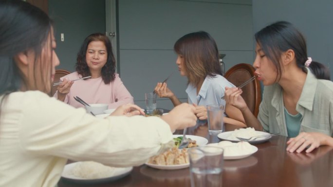 亚洲家庭吃中国菜，坐在后院的餐桌上玩得很开心。多代家庭共同享受消费理念。