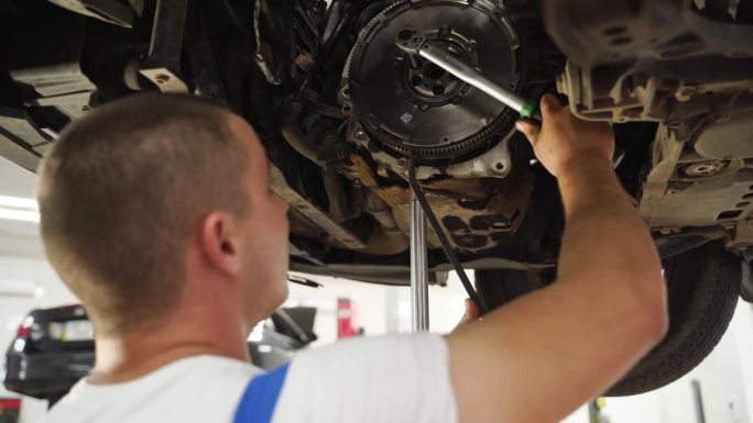 汽车修理工安装新的离合器总成。视频详细展示了变速箱的维修，重点是离合器片、盖板、释放轴承的安装。车间